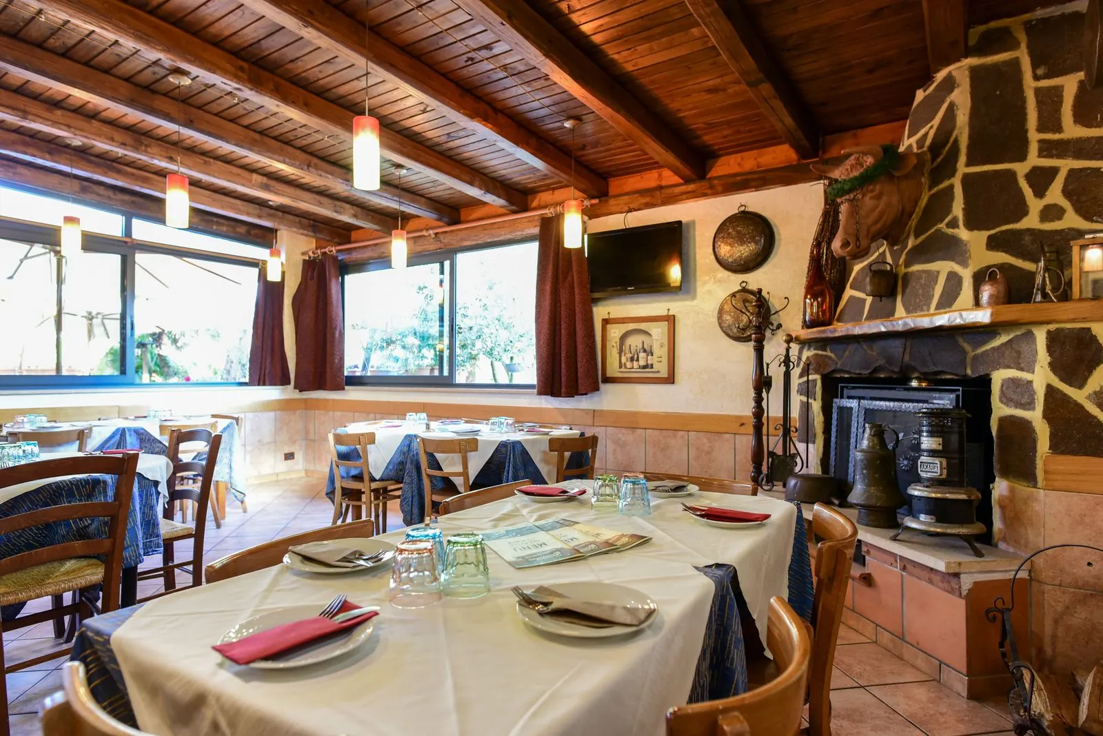 La sala camino: tavolo apparecchiato, travi in legno e camino in pietra